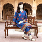 A mannequin wearing a vibrant blue floral printed 2-piece unstitched cotton lawn suit with detailed borders, displayed on a wooden bench in an outdoor courtyard setting.