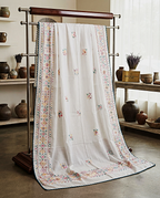 White chaddar with red and green floral botanical embroidery displayed on a rack