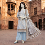 A mannequin posing in a sky blue 3-piece unstitched lawn suit with floral prints, paired with matching trousers and an elegant dupatta, standing in a historical courtyard.