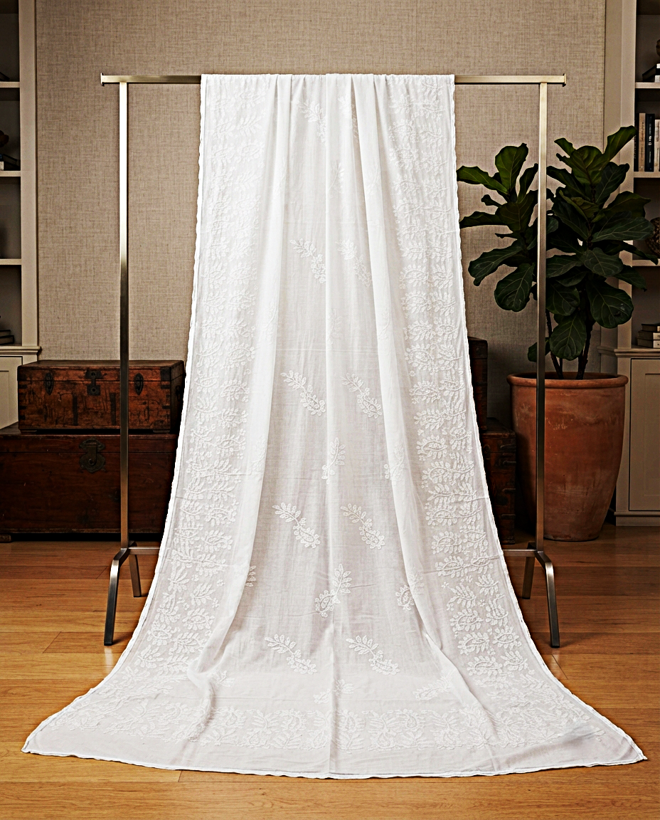 Classic white chaddar with intricate all-over white paisley and leaf embroidery hanging on a metal rack