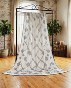 White chaddar featuring bold black geometric cross-stitch patterns displayed on a rack