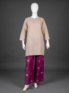 A traditional outfit displayed on a white mannequin against a dark gray studio background. The outfit consists of a light beige tunic with subtle silver embroidery and magenta wide-leg pants with silver floral motifs.