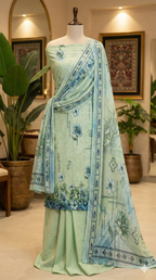 Light green saree with blue floral patterns on a mannequin against a decorative indoor background.