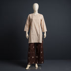A two-piece traditional outfit displayed on a white mannequin against a dark gray studio background. The set includes a light beige long-sleeve kurta with a split neckline and matching beige trousers, paired with dark brown wide-leg pants featuring a small beige floral pattern.