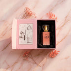 Top-down view of LUCK by ASAAH perfume in an open pink satin-lined box featuring a 'Thank You' card and delicate dried flowers.