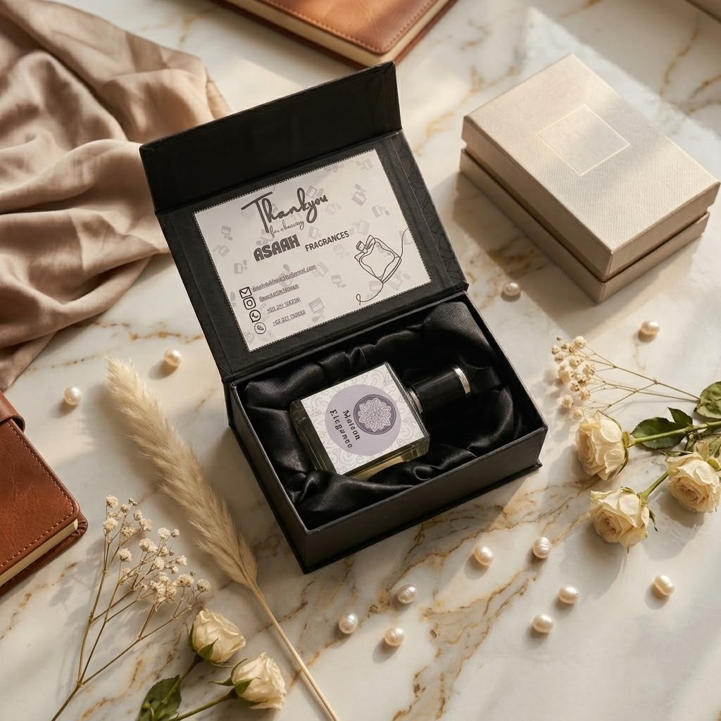 Maison Elegance 50ml perfume bottle by ASAAH Fragrance resting in an open satin-lined black gift box with cream roses and loose pearls on a marble table.