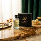 ASAAH Miss Perfume bottle standing next to its black presentation box on a marble table with a dark green velvet background.