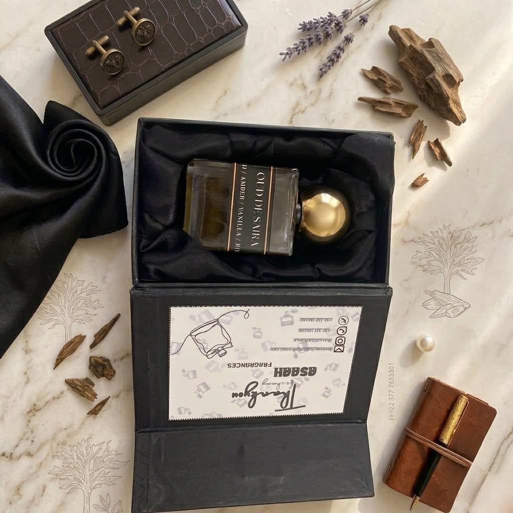 Top-down view of Oud De Saira perfume by ASAAH Fragrance sitting inside a premium satin-lined box next to raw oud wood chips and a leather notebook.